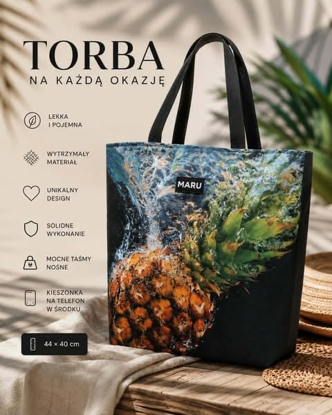 Black tote bag with colorful pineapple print design displayed on textured fabric with palm leaf shadows